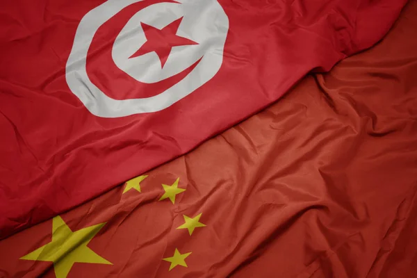 Falujące kolorowe flagi Chin i flagi narodowej Tunezji. — Zdjęcie stockowe