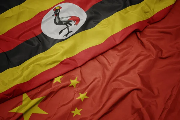 中国のカラフルな旗とウガンダの国旗を振る. — ストック写真