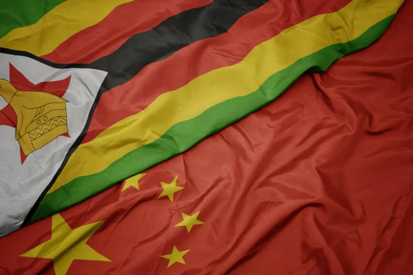 Agitant drapeau coloré de la Chine et drapeau national de zimbabwe . — Photo