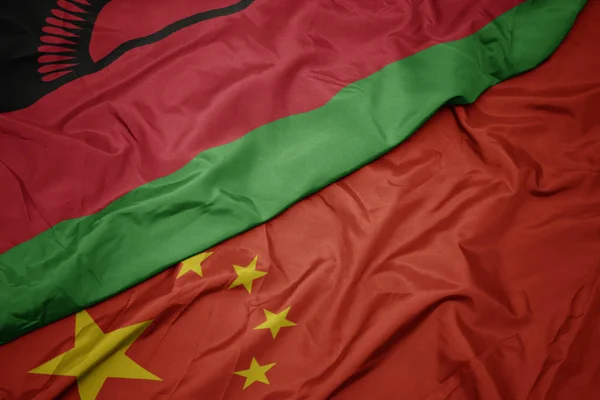 Mávající barevná vlajka Číny a národní vlajka Malawi. — Stock fotografie