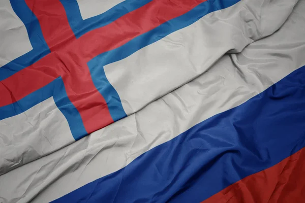 Schwenken bunte Flagge Russlands und Nationalflagge der Färöer-Inseln. — Stockfoto