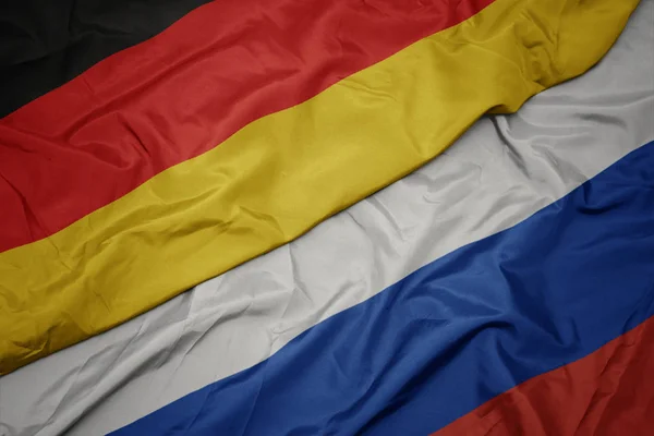 Orosz zászló, és Németország nemzeti zászlója hullámzó. — Stock Fotó