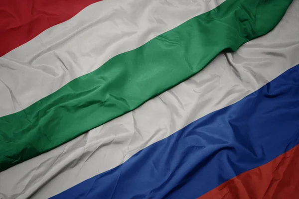 Waving colorful flag of russia and national flag of hungary. — Stock Photo, Image