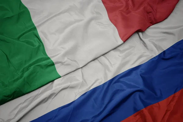Ondeando colorida bandera de Rusia y bandera nacional de Italia . —  Fotos de Stock
