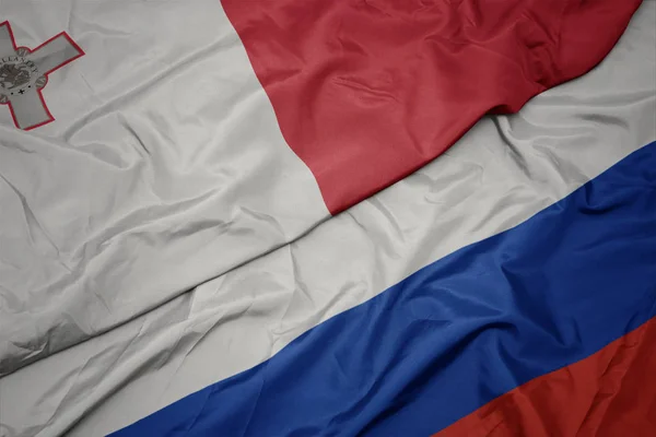 Sventolando bandiera colorata della Russia e bandiera nazionale di malta . — Foto Stock
