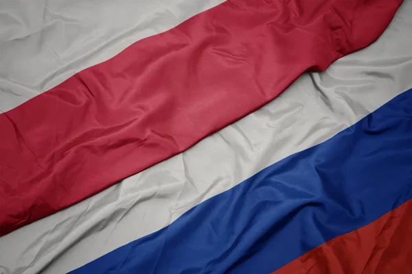 Mávající barevná vlajka Ruska a národní vlajky Polska. — Stock fotografie