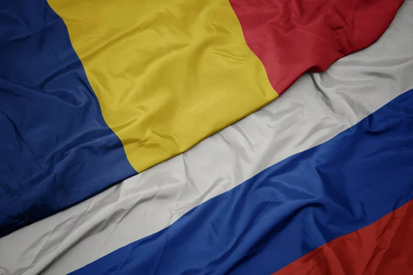 Waving colorful flag of russia and national flag of romania. — Stock Photo, Image