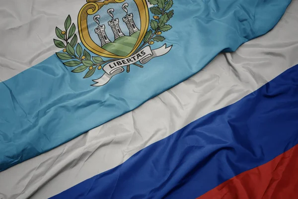 Sventolando bandiera colorata della Russia e bandiera nazionale di san marino . — Foto Stock