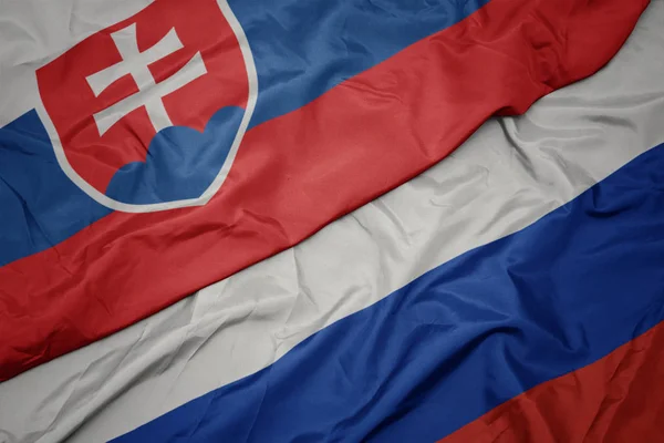 Waving colorful flag of russia and national flag of slovakia. — Stock Photo, Image