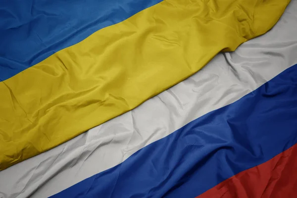 Schwenken bunte Flagge Russlands und Nationalflagge der Ukraine. — Stockfoto