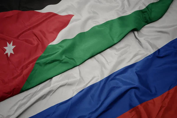 Ondeando colorida bandera de Rusia y bandera nacional de Jordania . — Foto de Stock