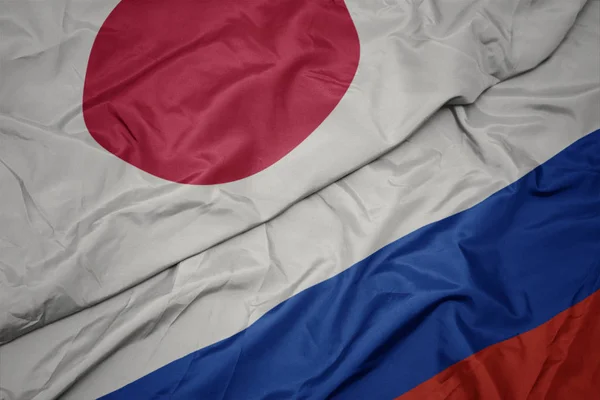 Ondeando colorida bandera de Rusia y bandera nacional de Japón . —  Fotos de Stock
