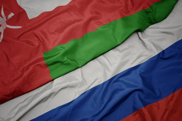 Waving colorful flag of russia and national flag of oman. — Stock Photo, Image