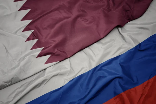 Falujące kolorowe flagi Rosji i flagi narodowej Kataru. — Zdjęcie stockowe