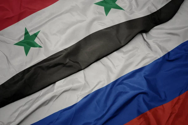 Zwaaiende kleurrijke vlag van Rusland en de nationale vlag van Syrië. — Stockfoto
