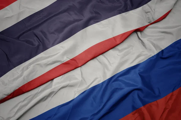Falujące kolorowe flagi Rosji i Narodowej flagi Tajlandii. — Zdjęcie stockowe