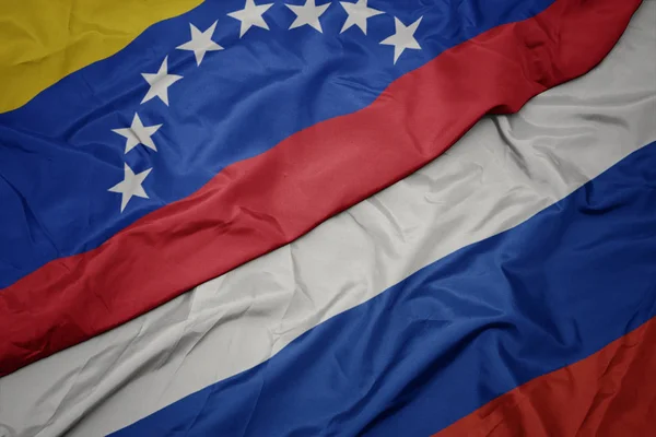 Mávající barevná vlajka Ruska a venezuelské vlajky. — Stock fotografie