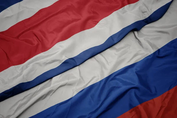 Falujące kolorowe flagi Rosji i flagi narodowej Kostaryki. — Zdjęcie stockowe