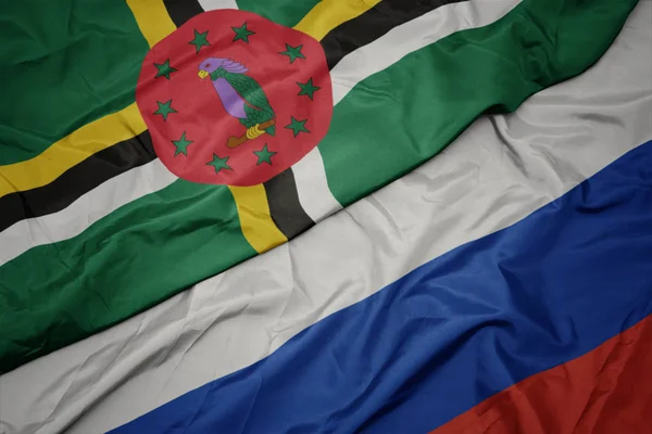 Acenando bandeira colorida da Rússia e bandeira nacional da Dominica . — Fotografia de Stock