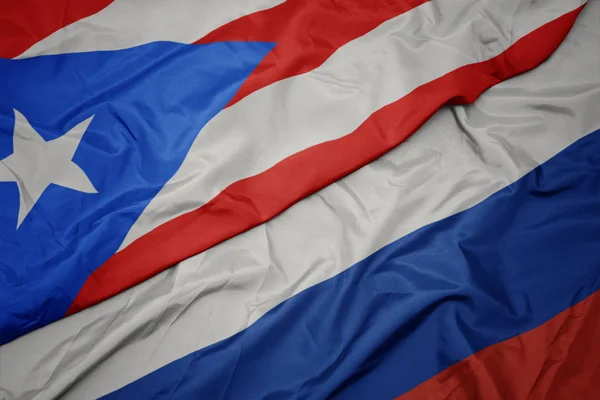 Ondeando colorida bandera de Rusia y bandera nacional de Puerto Rico . — Foto de Stock