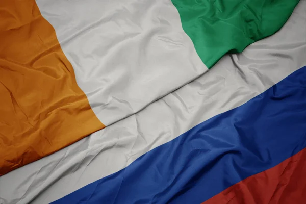 Размахивая красочным флагом России и национальным флагом Кот-Дивуара . — стоковое фото
