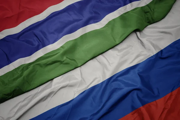 Schwenken bunte Flagge von Russland und Nationalflagge von Gambia. — Stockfoto