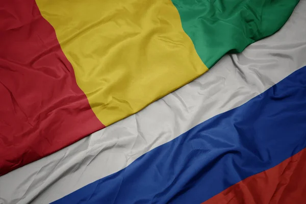 Waving colorful flag of russia and national flag of guinea. — Stock Photo, Image