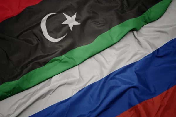 Ondeando colorida bandera de Rusia y bandera nacional de libya . — Foto de Stock