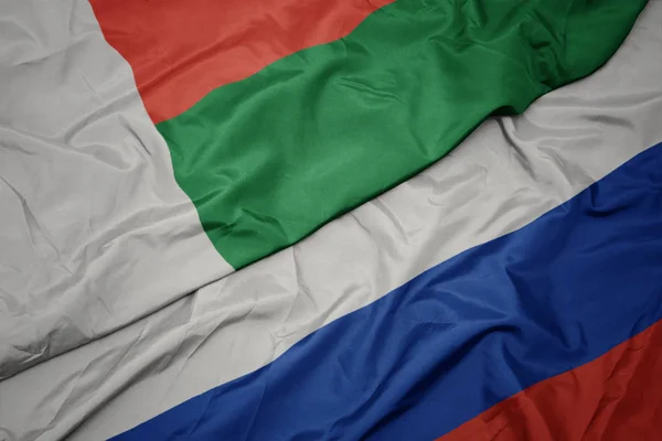 Acenando bandeira colorida da Rússia e bandeira nacional de madagascar . — Fotografia de Stock