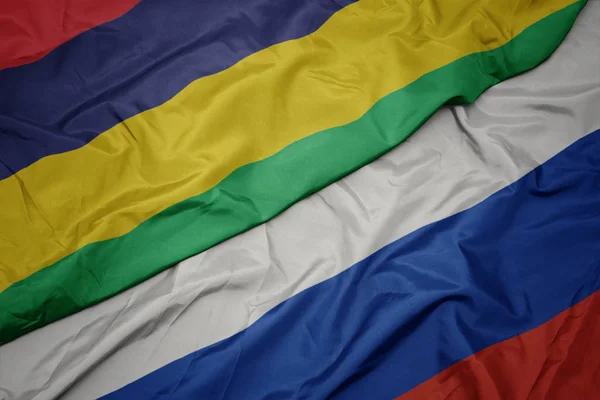 Ondeando colorida bandera de Rusia y bandera nacional de Mauricio . — Foto de Stock
