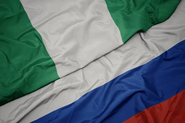 Ondeando colorida bandera de Rusia y bandera nacional de Nigeria . —  Fotos de Stock