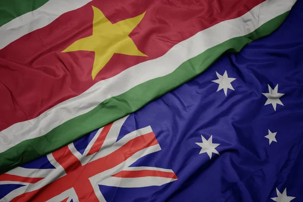 Waving colorful flag of australia and national flag of suriname. — Stock Photo, Image