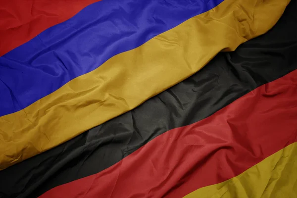 Zwaaiende kleurrijke vlag van Duitsland en de nationale vlag van Armenië. — Stockfoto