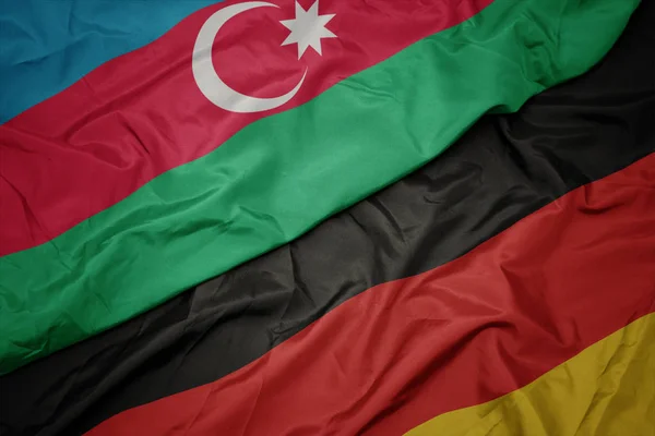 Schwenken bunte Deutschlandfahne und Nationalflagge von Azerbaijan. — Stockfoto