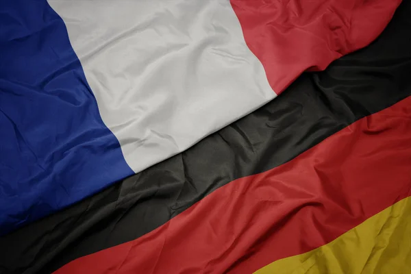 Zwaaiende kleurrijke vlag van Duitsland en de nationale vlag van Frankrijk. — Stockfoto