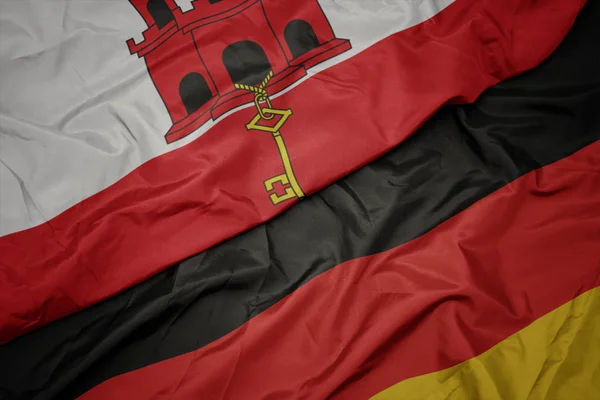 Ondeando colorida bandera de Alemania y bandera nacional de gibraltar . — Foto de Stock