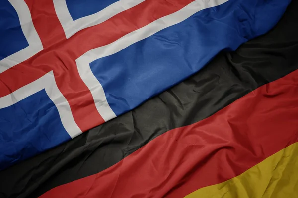 Ondeando bandera colorida de Alemania y bandera nacional de iceland . — Foto de Stock