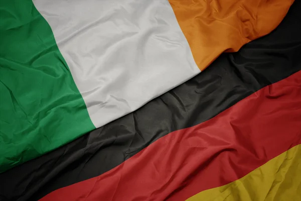 Acenando bandeira colorida da alemanha e bandeira nacional da Irlanda . — Fotografia de Stock