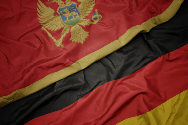Acenando bandeira colorida da alemanha e bandeira nacional de Monten= . — Fotografia de Stock