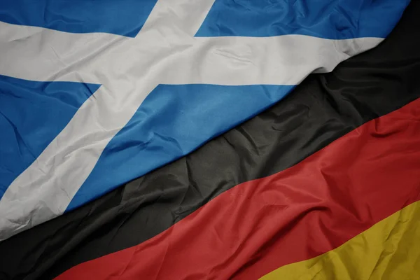 Falujące kolorowe flagi Niemiec i flagi narodowej Szkocji. — Zdjęcie stockowe