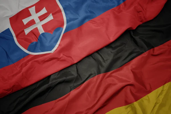 Falujące kolorowe flagi Niemiec i flagi narodowej Słowacji. — Zdjęcie stockowe