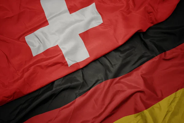Falujące kolorowe flagi Niemiec i flagi narodowej Szwajcarii. — Zdjęcie stockowe