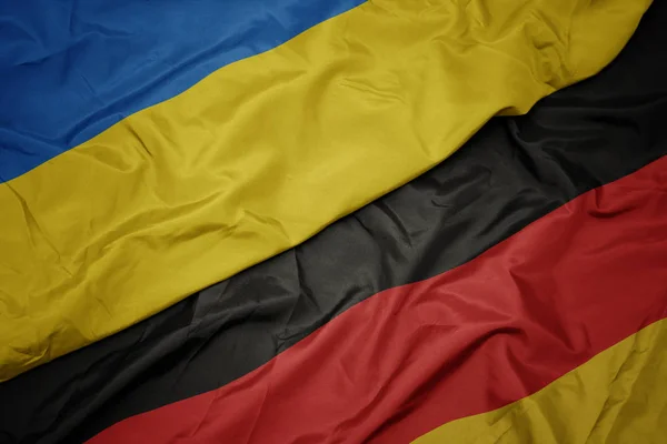 Acenando bandeira colorida da alemanha e bandeira nacional da Ucrânia . — Fotografia de Stock