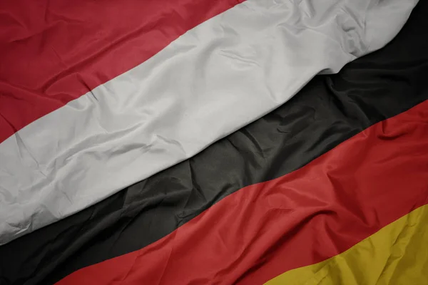 Acenando bandeira colorida da alemanha e bandeira nacional da indonésia . — Fotografia de Stock