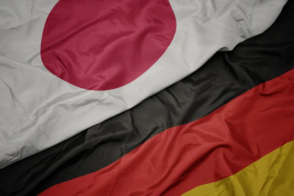 Acenando bandeira colorida da alemanha e bandeira nacional do japão . — Fotografia de Stock