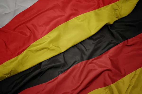 Acenando bandeira colorida da alemanha e bandeira nacional da ossétia do sul . — Fotografia de Stock