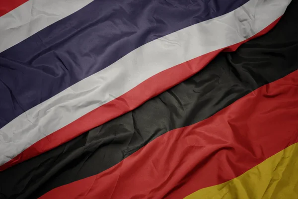 Acenando bandeira colorida da alemanha e bandeira nacional da Tailândia . — Fotografia de Stock
