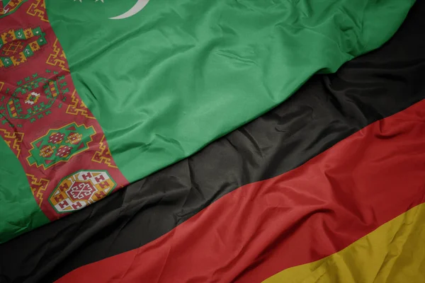 Acenando bandeira colorida da alemanha e bandeira nacional do Turquemenistão . — Fotografia de Stock
