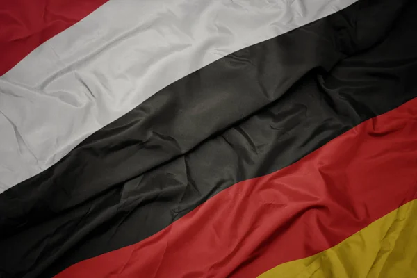 Acenando bandeira colorida da alemanha e bandeira nacional do Iêmen . — Fotografia de Stock