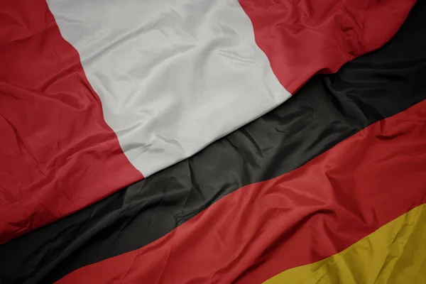 Zwaaiende kleurrijke vlag van Duitsland en de nationale vlag van Peru. — Stockfoto